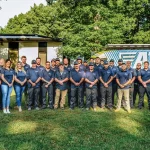 team photo of a1 staff on grass by branded service truck